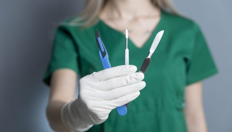 A female technician with rubber-glove holding scalpel other instruments